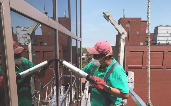 Commercial caulking contractor repairs the seal around a commercial window